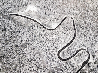 Aerial view of a road winding through snow covered forest