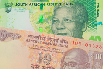 Fototapeta premium A macro image of a orange ten rupee bill from India paired up with a shiny, green 10 rand bill from South Africa. Shot close up in macro.