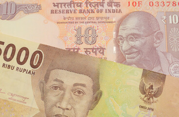 A macro image of a orange ten rupee bill from India paired up with a orange five thousand Indonesian rupiah note.  Shot close up in macro.