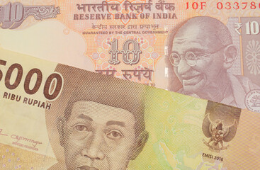 Fototapeta premium A macro image of a orange ten rupee bill from India paired up with a orange five thousand Indonesian rupiah note. Shot close up in macro.