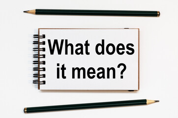 WHITE SPIRAL NOTEBOOK, TWO PENCILS WITH TEXT What does it mean