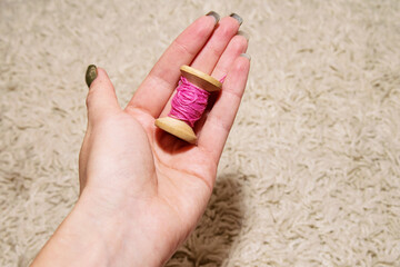 Pink spool of thread in the woman's left hand