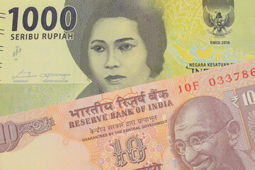 A macro image of a orange ten rupee bill from India paired up with a green one thousand bank note from Indonesia.  Shot close up in macro.