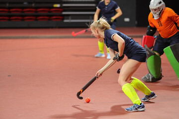 Naklejka premium Young woman player in attack at indoor hockey match