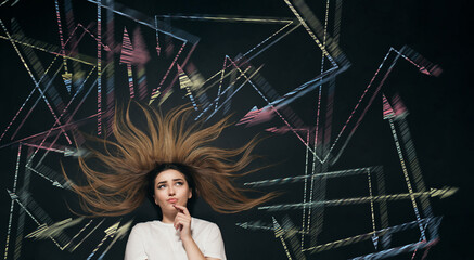 young woman making decision with arrows written on school blackboard above head, brainstorming concept, girl finding solution in tangled ways top view