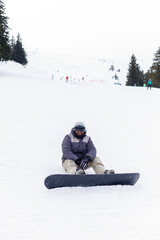 winter, leisure, sport and people concept - Snowboarder sitting at the top of a mountain and enjoying scenery