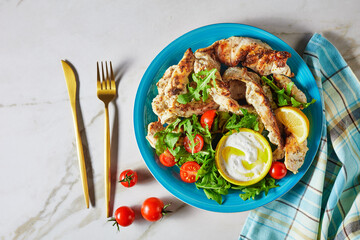 Grilled chicken with arugula salad on a blue plate