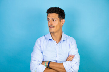 Young handsome man wearing blue shirt over isolated blue background skeptic and nervous,...