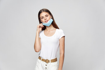 happy woman in medical mask holds her hand near her face and tilted her head 