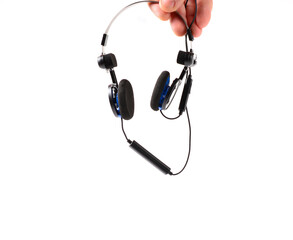 man's hand holds classic black headphones with bluetooth headset. isolated background. music...