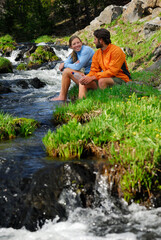 Naklejka premium Pair of Hikers relaxing with feet in a cold mountain stream