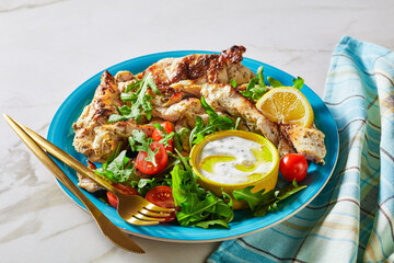 Grilled chicken with arugula salad on a blue plate