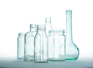 Transparent glass bottles of different shapes on white background, recycling material, waste...