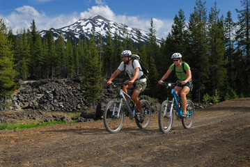 Fototapeta premium Mountain bikers traveling a dirt road under Mount Bachelor