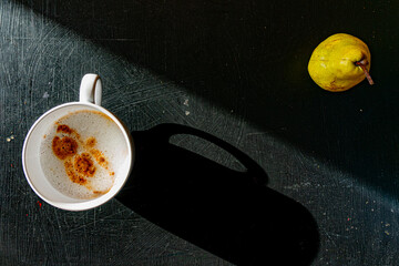 cup of coffee with milk and a pear