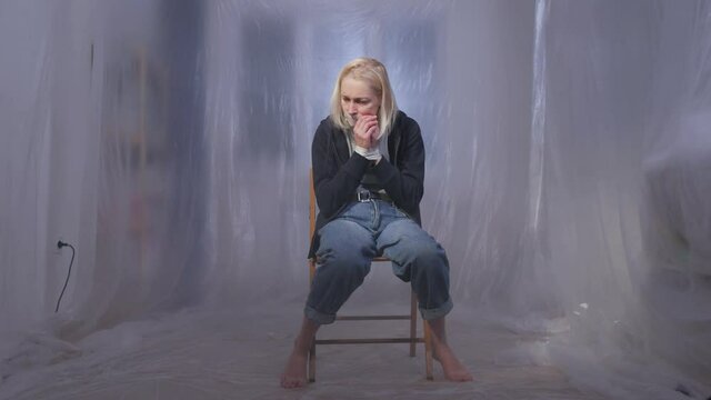 Female hostage sitting on a chair in a room with her mouth taped shut
