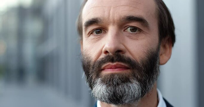 Portrait shot of Caucasian middle-aged man with beard standing outdoors and looking at camera. Pandemic coronavirus concept. Close up of male businessman.