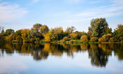 The forest river is reflected in the water. Beautiful autumn landscape