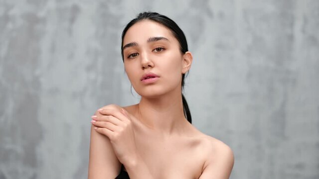 Seductive Asian woman with naked shoulders posing isolated. Medium close up shot on 4k RED camera