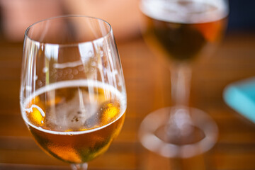 Blond beer served on a wineglass on a wooden table close up still