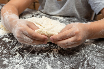 cute little girl kneading dough, preparing dough for baking
