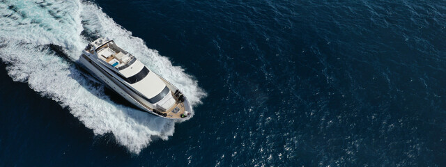 Aerial drone ultra wide photo of small luxury yacht cruising deep blue Aegean sea