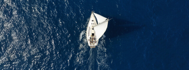 Aerial drone ultra wide photo of sailboat cruising deep blue sea