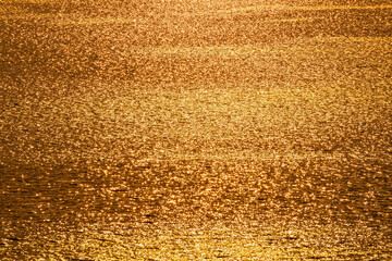 Golden sunlight reflects the streak wave on the water surface in a high view during sunrise and sunset for abstract texture background 