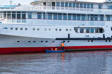 Boat with workers near the cruise ship, carrying out maintenance.