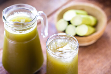 The cane juice or garapa is the liquid extracted from the sugar cane in the milling process. Sweetened, organic drink with pieces of cane in the background