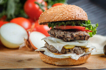 Juicy Burger on a wooden Board, against the background of vegetables.