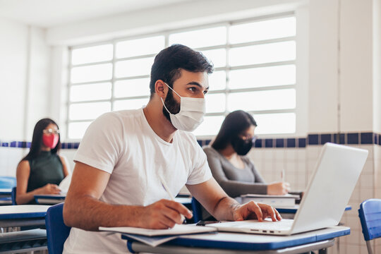 Brazilian college students wearing face masks sitting at the desk in the classroom. Concept of reopening of educational institutions in the COVID-19 pandemic