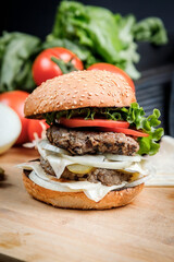 Tasty grilled burger with with beef, cheese, vegetables.  Delicious grilled Cheeseburger on a dark background. 