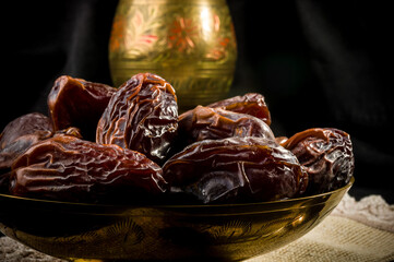 Big luxury dried date fruit in bowls on a linen napkin, kurma ramadan kareem concept, close up.