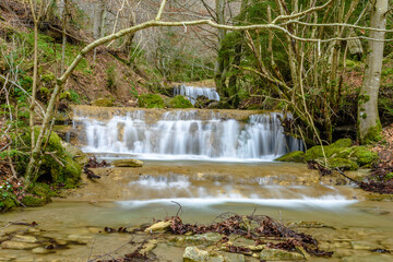 Stream of water in the forest with a little waterfall
