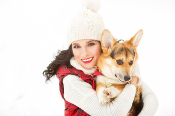 Outdoors lifestyle image of pretty girl hugging puppy corgi in the park. Beauty face. Wearing stylish knitted hat, sweater, vest. Playing with the dog. Close-up. Animal love concept. White background