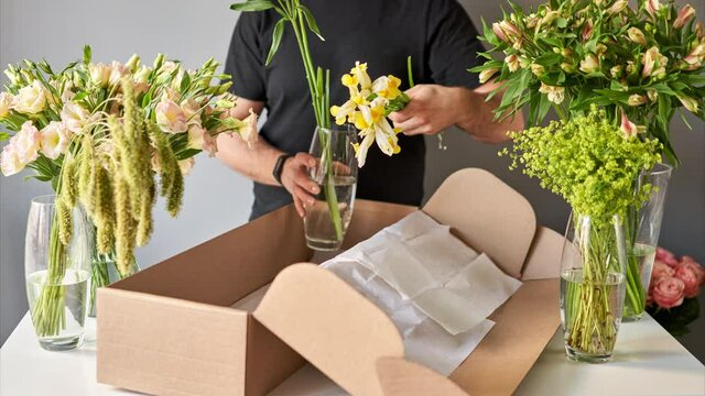 Stop motion, step by step a male florist puts a set of flowers in a carton box.. Flowers bunch, set for home. Fresh cut flowers for decoration home. European floral shop. Delivery fresh cut flower.