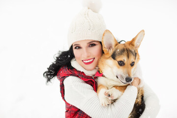 Outdoors lifestyle image of pretty girl hugging puppy corgi in the park. Beauty face. Wearing stylish knitted hat, sweater, vest. Playing with the dog. Close-up. Animal love concept. White background