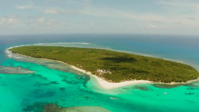 Tropical island in the ocean with palm trees on white sand beach. Daco island, Philippines. Summer and travel vacation concept
