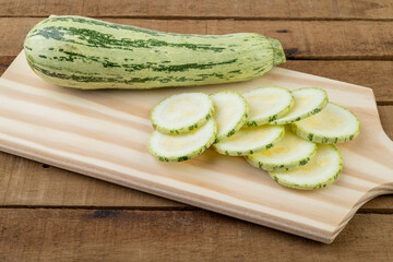Raw zucchini with slices over wooden board