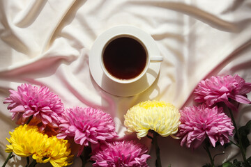 Morning coffee in bed. A cup of coffee and lovely autumn flowers chrysanthemums in bed with soft shadow. Lifestyle, morning concept. Top view, flat lay
