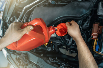 Pouring new engine oil from canister into motor funnel at car service, close up.