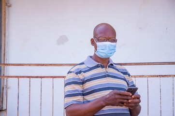 handsome elderly african man wearing face mask preventing, prevented himself from the outbreak in...