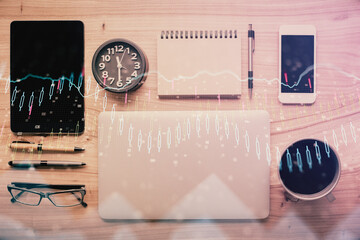 Double exposure of forex graph hologram over desktop with phone. Top view. Mobile trade platform concept.