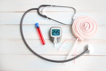 digital glucometer, laboratory test tube with blood, medical stethoscope, sweet marshmallow on a stick, healthy food concept, diet choice