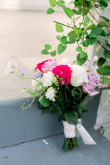 A bouquet of fresh pink and white flowers sitting on the steps under some vining green flowers.