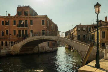Fototapeta na wymiar Venice bridge over canal with boat and blue sky in sunshine