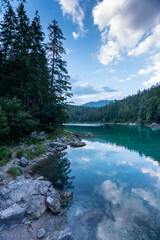 Beautiful Eibsee lake in Bavaria Germany with trees, clouds and mountains reflecting in the crystal clear water