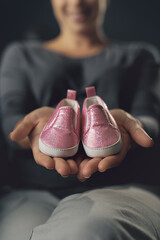 Pregnant woman showing cute baby shoes