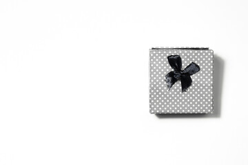 A small grey polka dot gift box with a black bow on a white background with copy space.The act of giving gifts and celebrating.